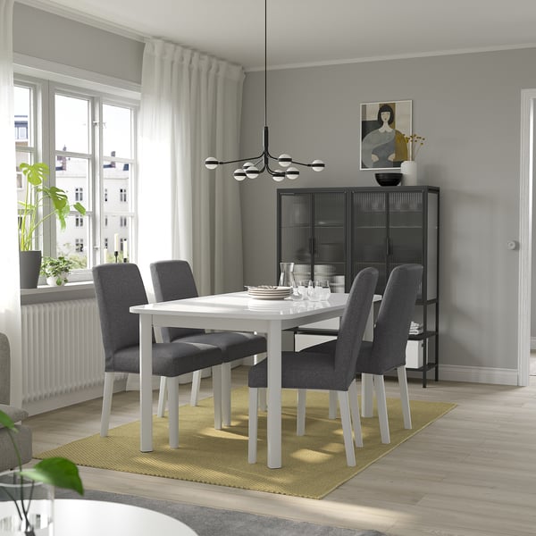 Modern dining room with STRANDTORP extendable table, black chairs, yellow rug, large window, black sideboard, abstract art, and a hanging lamp.