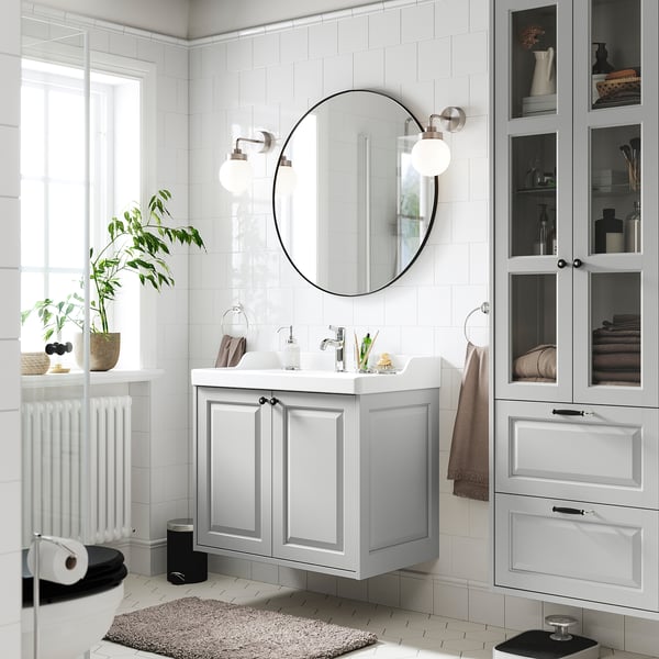 Modern bathroom with TÄNNFORSEN grey cabinet, round mirror, glass shelves. Clean lines, classic design, spacious layout.