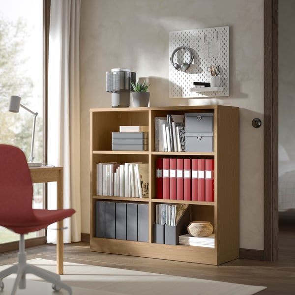 Wooden bookshelf with books near a window.