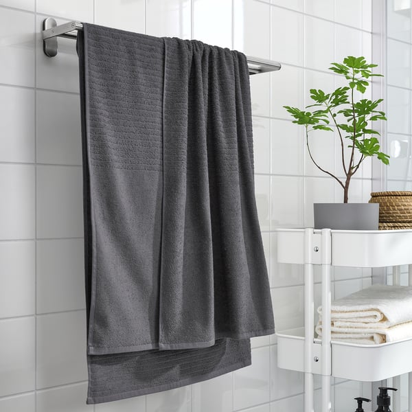 Gray VÅGSJÖN towel on wall, next to towels & plant.