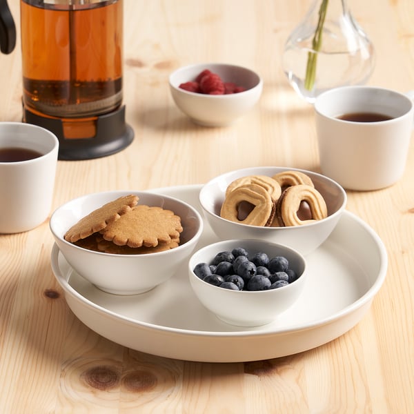 A kitchen table with cookies, berries, and coffee in cups around a rotating turntable holding more snacks.