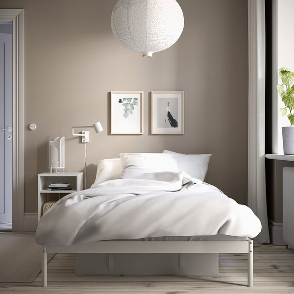 Minimalist bedroom with VEVELSTAD bed, white linens, pendant light, and simple decor.