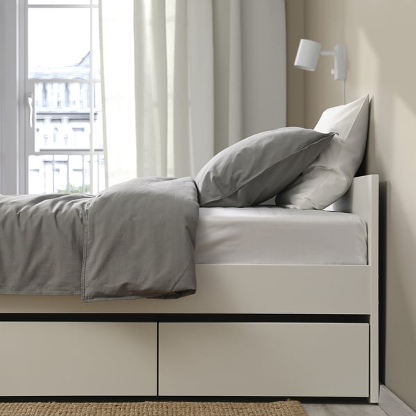 Modern bed frame with two storage drawers under grey bedding.