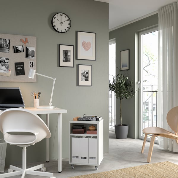 Modern home office with VIHALS white desk, chair, and storage unit, featuring a laptop, plants, and wall art.