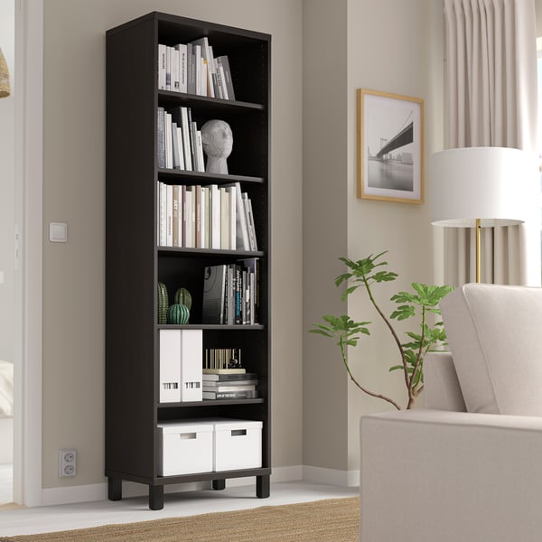 Must BESTÅ raamaturiiul raamatutega, dekoor, akna, tooli, lambi, taimega.