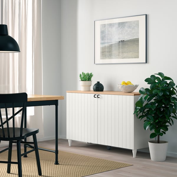 BESTÅ puhvetkapp pehmelt sulguvate uste, laua, toolide ja sisekujundusega minimalistlikus toas.