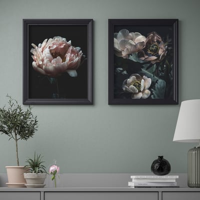 Konsoollaua kohal ripuvad kaks raamitud lillekunstiprinti, millel on lamp, vaas ja taim.