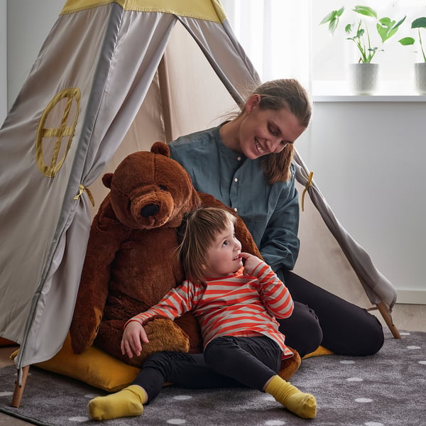 Hallis tiibis istuvad kaks inimest koos suure pruuni kaisukaruga, mida soovitatakse kaisutamiseks ja mängimiseks, sobib alates 18. elukuust.