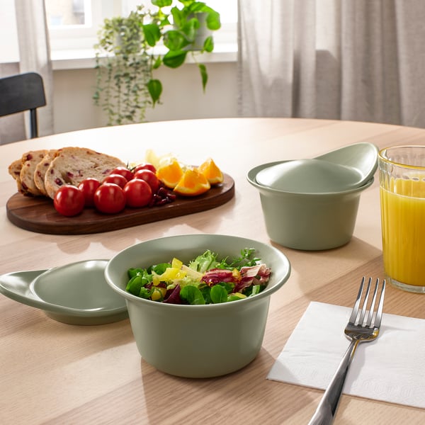 Söögilaud tervislike roheliste kaussidega, mis on täidetud salati, leiva, tomatite ja apelsinimahlaga.