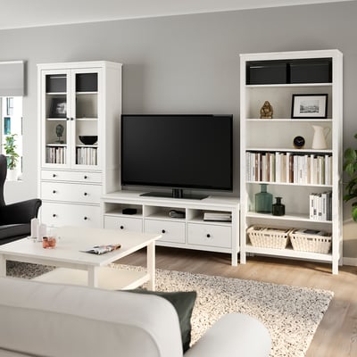 HEMNES elutoa komplekt: valge televiisori alus, raamaturiiul raamatutega, diivanilaud vaibal.
