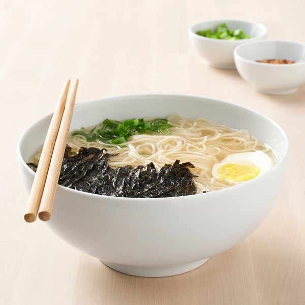 Kauss ramen-nuudleid lisanditega, söömiseks valmis. Söögipulgad küljel.