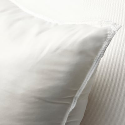 Lähivõte pehmest valgest padjast, mis näitab selle pehmet, tekstuurset kangast ja lihavat, kutsuvat disaini.