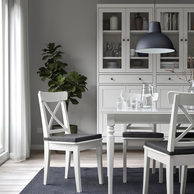 Kaasaegne söögituba JUSTINA valgete toolide, elegantse laua, ripplambi ja halli klaasnõudega kapiga. Minimalistlik sisekujundus.