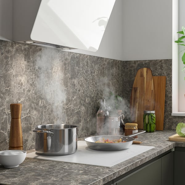 Kaasaegne köök marmorist tagaküljega, aktiivne toiduvalmistamine köögiviljadega ja organiseeritud maitseained.