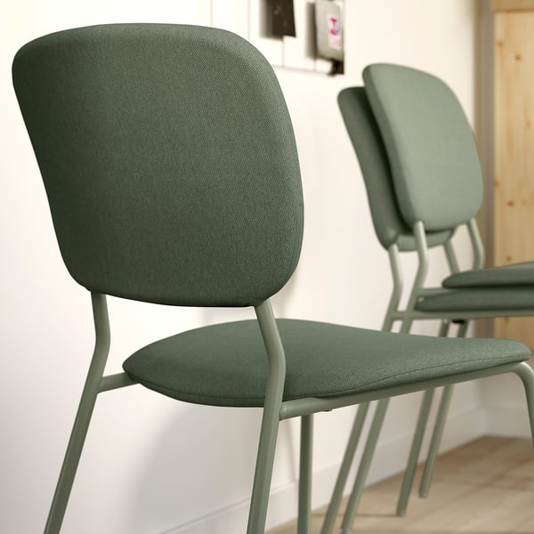 Kaks rohelist polsterdatud tooli metallist jalgadega, mis on loodud mugavuse ja vastupidavuse tagamiseks, virnastatavad mugavaks hoiustamiseks.