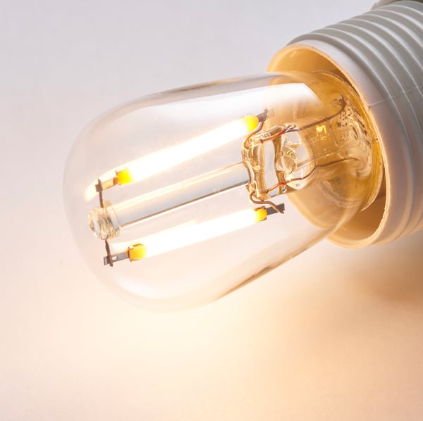 Lähivõte energiasäästlikust LUNNOM LED-pirnist, mis näitab selle sooja sära ja läbipaistvat klaasist disaini.
