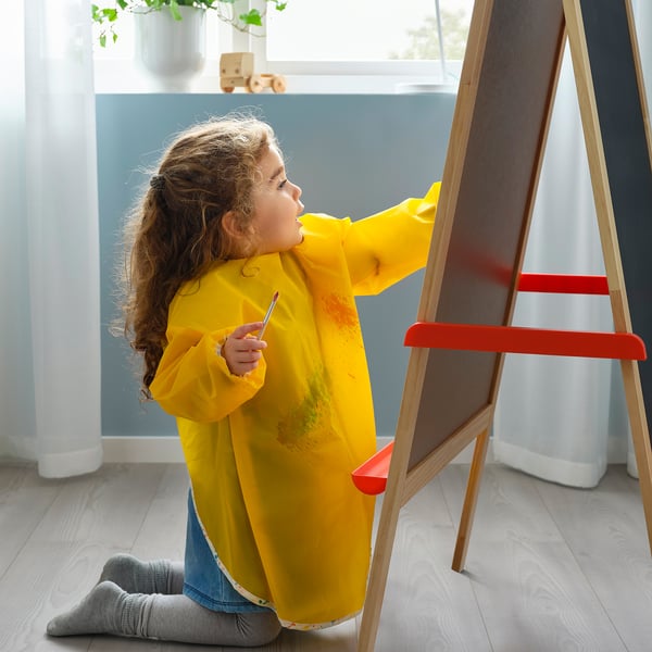 Kollase särgiga laps joonistab molbertile. Toode: ikea MÅLA.
