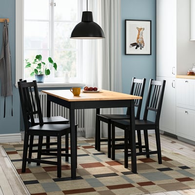Hubane einestamine IKEA laua ja toolidega, erksa vaibaga, musta lambiga, rebase seinakunstiga.