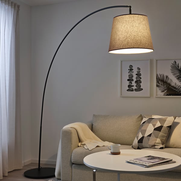 Kaasaegne elutuba SKOTTORP põrandalambi, geomeetriliste patjade ja hajutatud valgustusega.