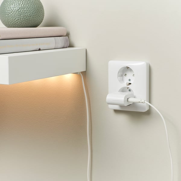 Ühendatud usb-ga seinalaadija, mis on paigutatud raamatute ja dekoratiivse keraga riiuli alla.