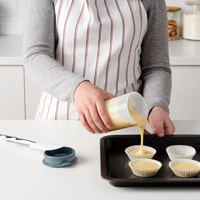Inimene, kes valab gradueeritud šeikerist vedelikku muffinitopsidesse.