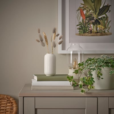 Valge vaas kuivatatud lillede ja raamatutega.