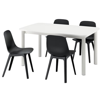 Valge IKEA STRANDTORP pikendatav söögilaud nelja musta tooliga. Toolidel on kumerad istmed ja mustad jalad.