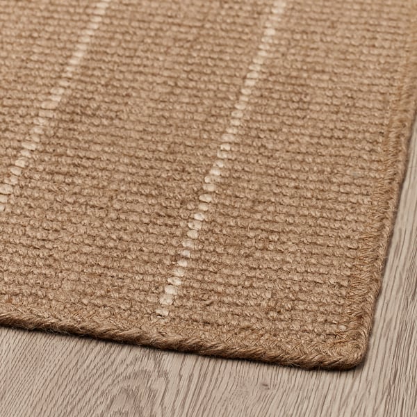 Punutud servadega džuudist uksematt, mis on kenasti puitpõrandale asetatud, näidates keerukat kudumist ja loomulikku tekstuuri.