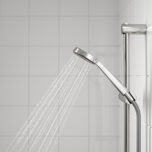 Kroomitud käsidušš täieliku pihustusfunktsiooniga, mis on paigaldatud hoidikule, vabastades vett laia kaarega vastu plaaditud seina.