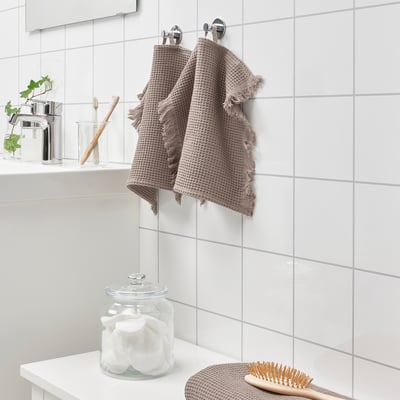 Vannituba valgete plaatide ja kahe VALLASÅN rätikuga. Üks puuvillaste ümmargustega volditud, pintsel kõrval. Imavad, kiiresti kuivavad vahvlirätikud.