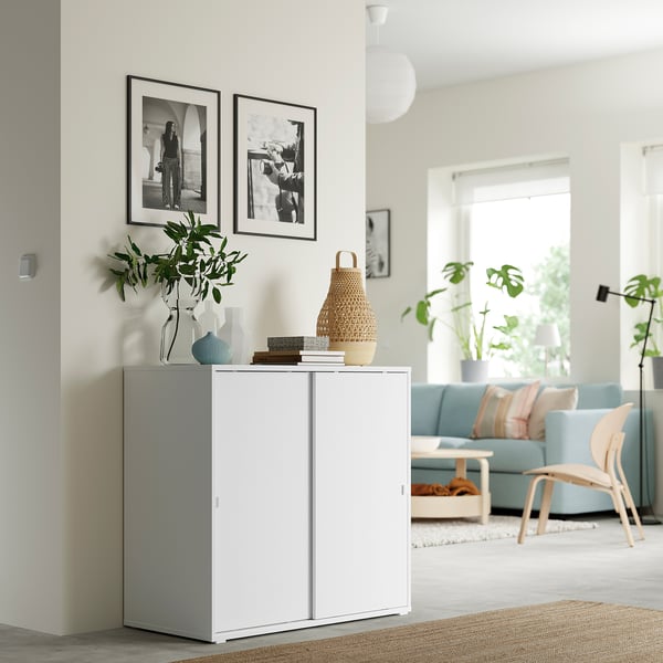 Minimalistlik elutuba, valge hoiukapp, diivan ja tool, loomulik valgus.