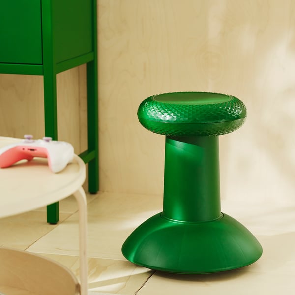 IKEA erkroheline YXSTABY taburet, mis on valmistatud taaskasutatud plastikust, ainulaadne pöidlapulgast inspireeritud kujuga, seisab kõrgel ümmarguse laua ja mängupuldi lähedal.