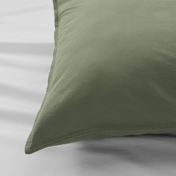 A close-up of a green pillowcase on a white surface, showcasing its soft, textured cotton fabric.