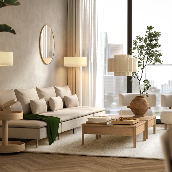 Modern living room with white sofa, beige ÄRENDE rug, wooden table, floor lamps, and large windows.