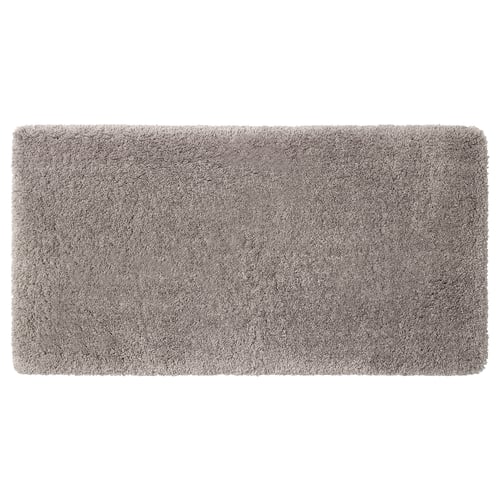 A plush ALMTJÄRN bath mat in beige. Its rectangular, soft, and made from recycled polyester, offering warmth and absorbency.
