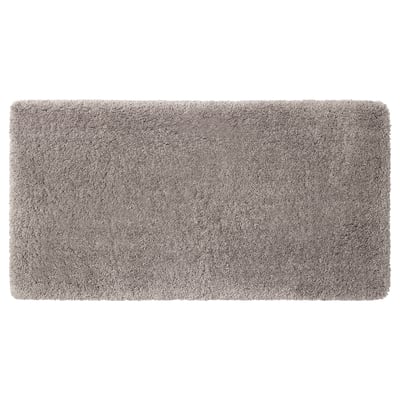 A plush ALMTJÄRN bath mat in beige. Its rectangular, soft, and made from recycled polyester, offering warmth and absorbency.
