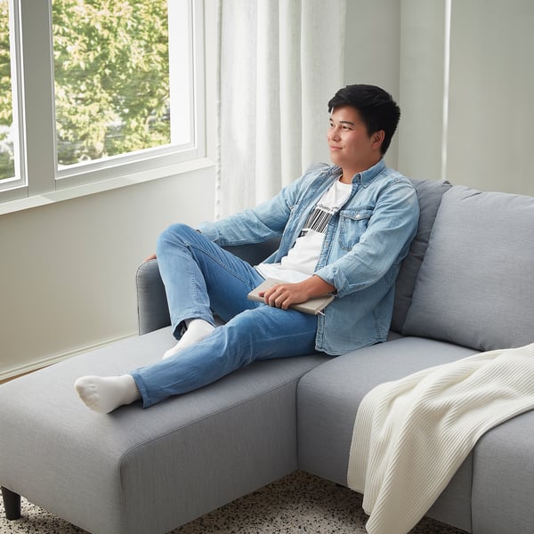 Person in denim relaxes on sofa, gaming.