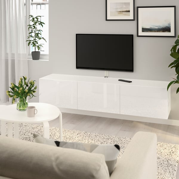 Minimalist living room with BESTÅ tv bench, large tv, storage, and a cosy sofa. Natural light, flowers, and wall art.