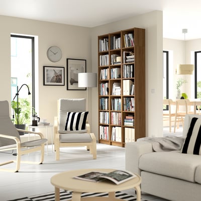 Modern living room with BILLY bookcase, grey sofa, armchairs, and natural light.