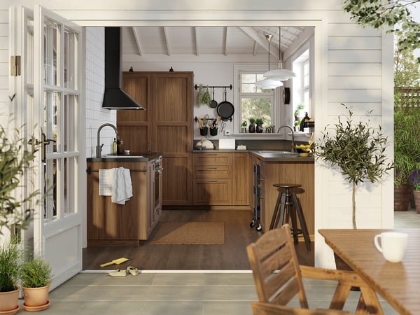 Modern kitchen with brown walnut cabinets, stainless steel appliances, and wooden floor.
