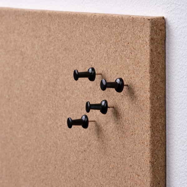 Cork bulletin board with black pushpins neatly arranged, demonstrating quality and simplicity.