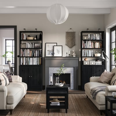 Modern living room with HAVSTA black bookshelf, cream sofas, grey rug, fireplace.