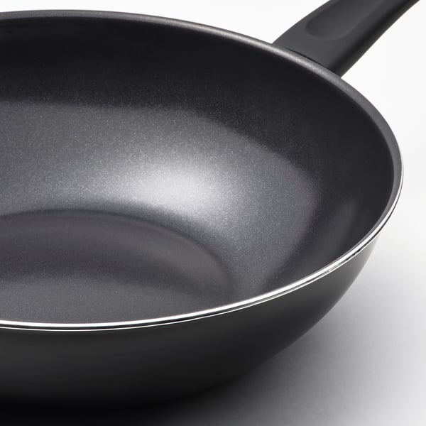Black non-stick wok with two sturdy handles and a reflective interior, positioned on a white surface.