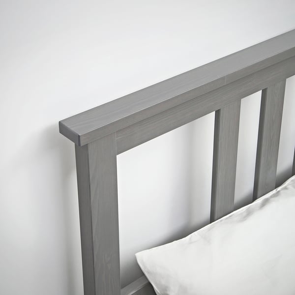 Close-up of grey wooden bed frame with sleek design. Shows clean lines and sturdy construction. White bedding is partially visible.