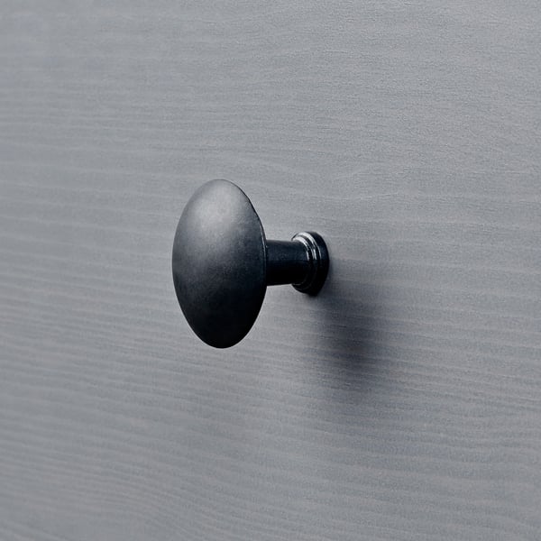 Small black circular hook on a textured grey wall.