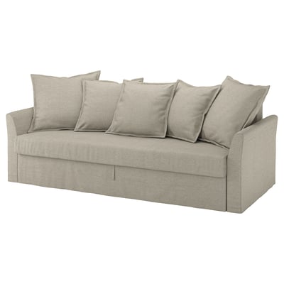 A beige HOLMSUND sofa with six cushions, designed for easy conversion into a bed, featuring a storage space and a modern, inviting design.