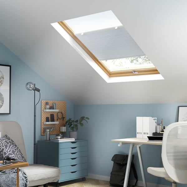 Bright home office under large skylight. Desk, chair, plants. Blue walls, grey furniture. HORNVALLMO blind blocks light.
