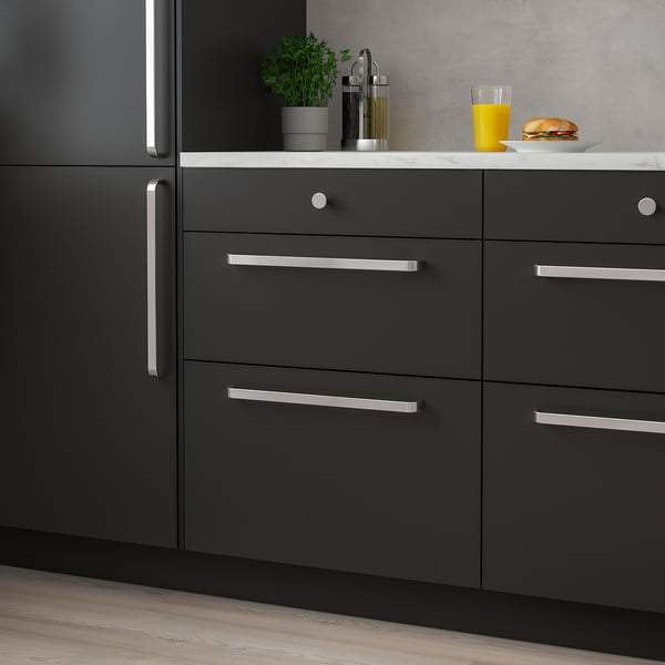 Modern kitchen with black KALERUM handles, marble countertop, plant, food, orange juice.