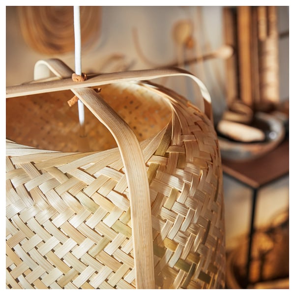A KNIXHULT bamboo hanging lamp with soft glowing light, hand-woven, natural colour.