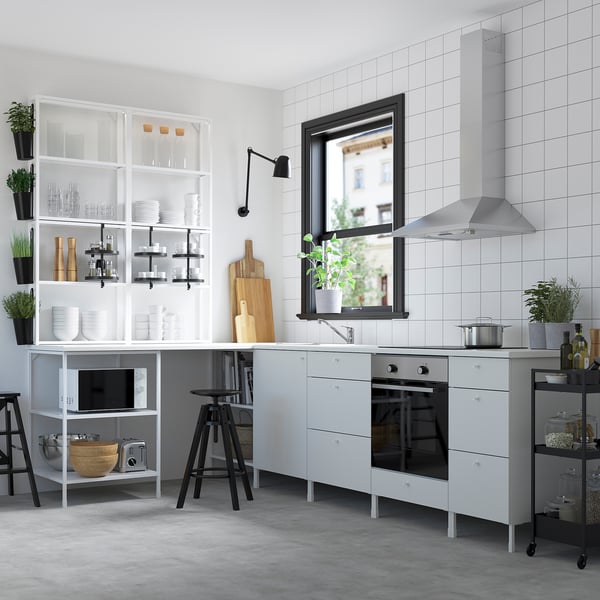Modern white kitchen with glossy tiles, white cabinets, built-in oven & microwave. Black stools & fixtures. Window above sink.
